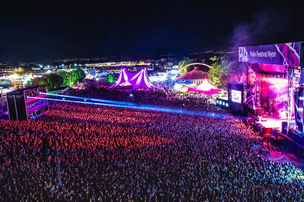 Photographie du Paléo Festival montrant une scène en plein concert avec un public dense et des conditions de production professionnelles, illustrant l’organisation structurée de l’accueil presse et des zones dédiées aux photographes accrédités.