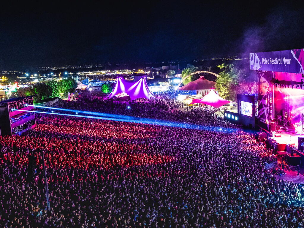 Photographie du Paléo Festival montrant une scène en plein concert avec un public dense et des conditions de production professionnelles, illustrant l’organisation structurée de l’accueil presse et des zones dédiées aux photographes accrédités.